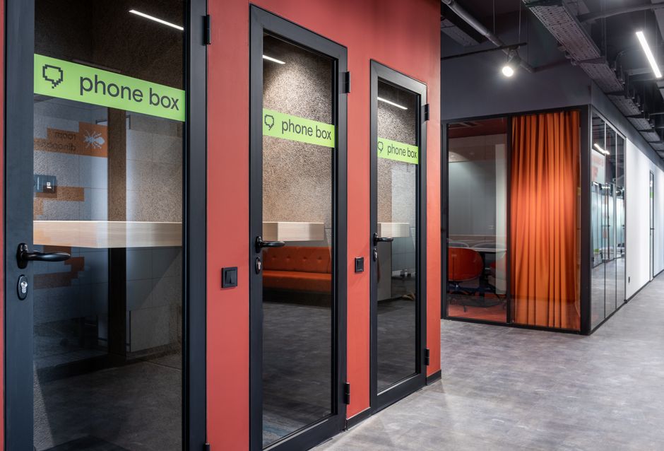 Phone boxes with inscription on glass doors and conference room with red curtain and chairs in hall of contemporary business center